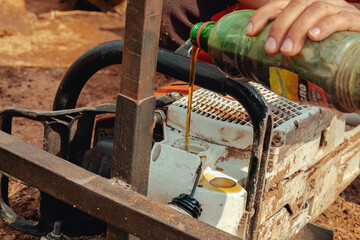 Closeup of lumberjack pouring oil into the chainsaw oil tank