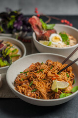 spicy asian noodles with baby octopus side view on served table background closeup. Selective focus