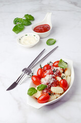 Gnocchi with tomatoes, red sauce, cheese and basil leaves