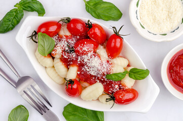 Gnocchi with tomatoes, red sauce, cheese and basil leaves