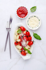 Gnocchi with tomatoes, red sauce, cheese and basil leaves