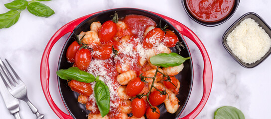 Gnocchi with tomatoes, red sauce, cheese and basil leaves