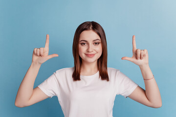 Photo of young pretty girl indicate fingers empty space advertise choice select isolated over teal...