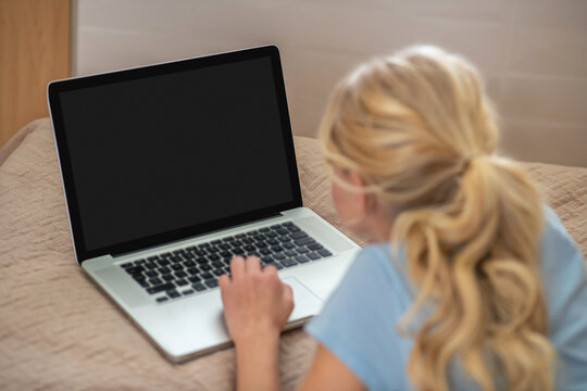 A blone girl lying on the bed and doing her lessons