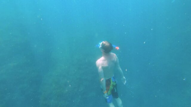 Young caucasian man with a snorkel mask and fins swims freediving underwater. Shooting with an action camera