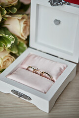 wedding rings lie on a beautiful box with flowers as bridal accessories