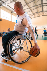 Close up photo of wheelchairs and handicapped war veterans playing basketball on the court