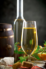 White wine in a bottle and glass on a background of an oak barrel and grapes
