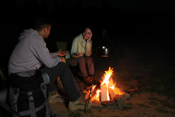 Couple near bonfire outdoors in evening. Camping season © New Africa