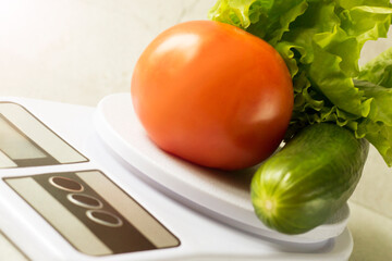 Tomato and cucumber on kitchen scales, healthy vegetables