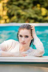 Portrait of a beautiful girl with wet hair dressed in a white shirt standing chest-deep in water...