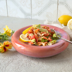 salad plate with tomatoes, crayfish tails and avocado on a light table