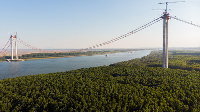 Panoramic aerial drone view from above of the suspended bridge over danube river, under construction, between Braila and Tulcea cities in Romania