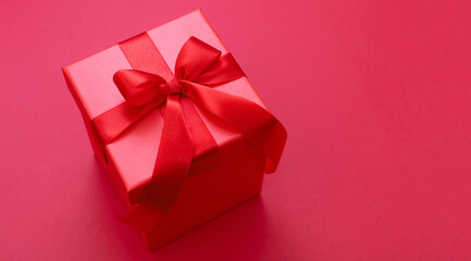 Gift box red ribbon and bow on red background, Christmas present satin curly decoration,