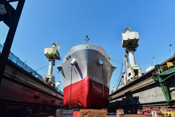 Cargo ship with shadows moored in floating dry dock yard during maintenance and repair