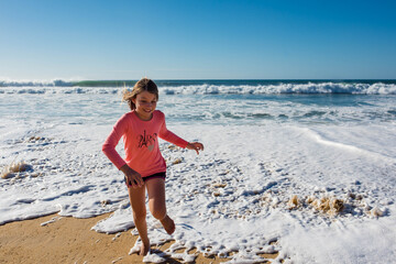 Fototapeta na wymiar cute little girl having fun barefoot by the ocean
