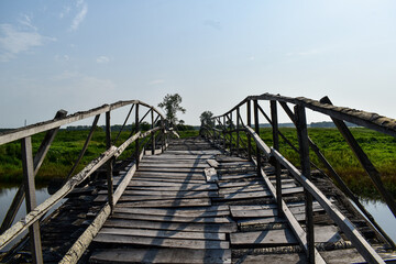 Obraz premium An old rough wooden bridge over the river.