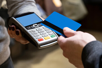 Close-up of a woman's hand with a terminal for reading credit cards for payment.