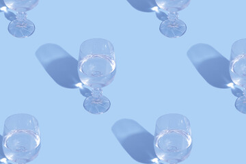 Glasses with water and shadow pattern on blue background