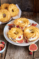 Obraz na płótnie Canvas Choux rings with cream, figs and raspberries. Wooden background, side view.