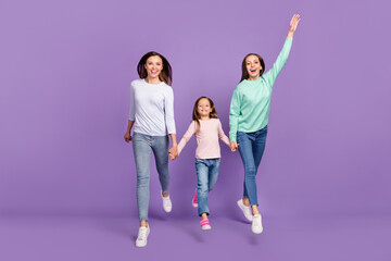 Fototapeta premium Photo of sweet funny daughters mom dressed casual sweaters holding hands jumping high isolated purple color background