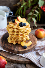 Belgian waffles with nectarine and blueberries. Side view, wooden background. Rustic.