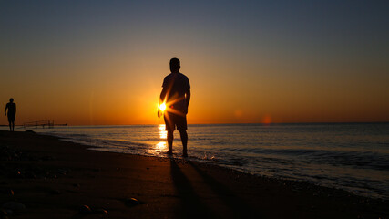 Fototapeta premium Young man walking on the beach at sunset