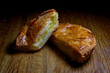 two halves of a cupcake, sponge cake and custard, Basque cake, gateau basque, one half on top of the other, cream inside, golden on top, placed on a wooden table, sweet dessert, custard, custard pie, 