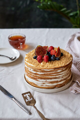Honey cake decorated with blueberries, figs and strawberries. Side view. Layer cake.