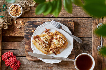 Pancakes with walnuts, chocolate and mascarpone cream. Wooden background, top view.