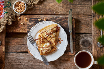 Pancakes with walnuts, chocolate and mascarpone cream. Wooden background, top view.