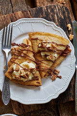 Pancakes with walnuts, chocolate and mascarpone cream. Wooden background, top view.