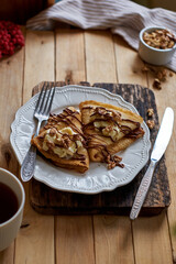 Pancakes with walnuts, chocolate and mascarpone cream. Wooden background, side view.