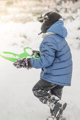 the child clears the snow with a shovel on the street