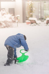 the child clears the snow with a shovel on the street