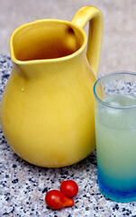 Pitcher of fresh water, glass of Pastis with ice cubes and cherry tomato on a table in Provence for aperitif