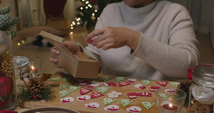 Asia woman enjoy fun make craft gift for night party tasty snack cooking recipe on table in good warm relax time. Cute smile gingerman mold shape bakery icing sugar glaze with red green white color.