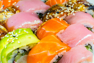 Tasty Colorful assorted Set of different type Sushi. Dinner in Japanese style. Healthy food. Filadelfia and Maki sushi rolls with Avocado, Tuna, Salmon, fish and Prawns. Close up view. Wallpaper.