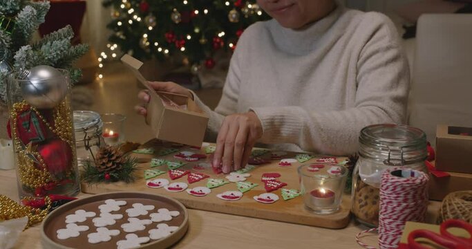 Asia woman enjoy fun make craft gift for night party tasty snack cooking recipe on table in good warm relax time. Cute smile gingerman mold shape bakery icing sugar glaze with red green white color.