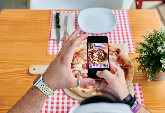 Man taking pictures of a pizza with his phone