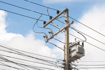 High voltage cement electric pole with drop fuse and transformer with blue sky white cloud close-up.