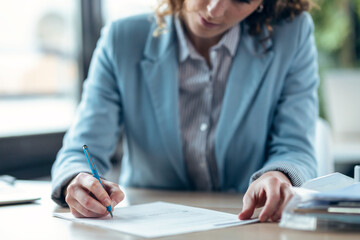 beautiful woman signing bank loan agreement with real-estate agent to buying the house in a real...