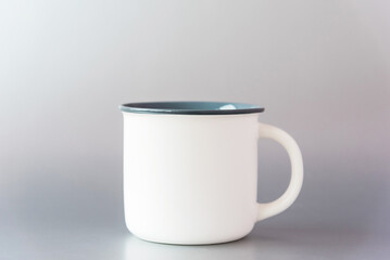 New white blank template metal mug with big handle for drinks reflected on shining surface stands on light grey background, copy space, mockup