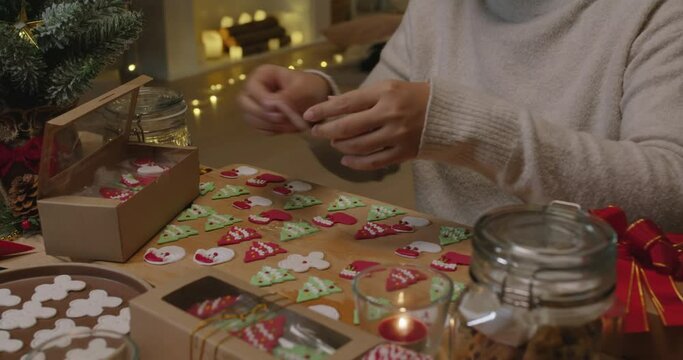 Asia woman enjoy fun make craft gift for night party tasty snack cooking recipe on table in good warm relax time. Cute smile gingerman mold shape bakery icing sugar glaze with red green white color.