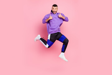 Fototapeta na wymiar Full length photo of young cheerful man jump show thumbs-up select suggest advertise isolated over pink color background