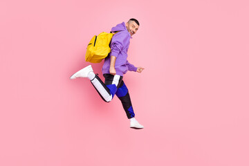 Full length profile photo of cool young brunet guy jump wear hoodie bag pants shoes isolated on pink background