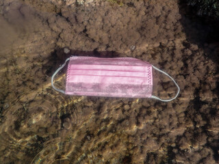 Concept of ocean pollution with a used one way facemask floating underwater, Pollution of ocean...