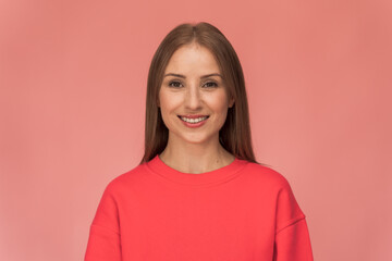 Waist up portrait view of a beautiful happy young woman standing on a pink wall and sincerely smiling. Modern girl smiling broadly at camera, while standing against pink background