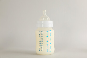 Feeding bottle with infant formula on light grey background. Baby milk