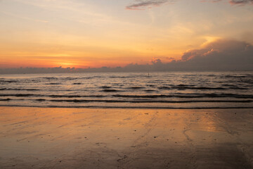 The golden-orange sunlight hits the sea and sand.